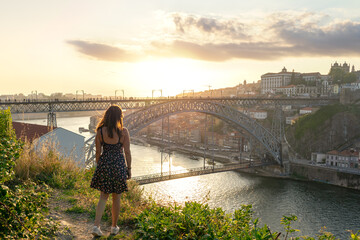 dom luiz brige in Porto on the riverside of Duero river cityscape at sunset from above with a tourist woman - obrazy, fototapety, plakaty