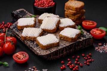 Delicious salty rectangular wheat croutons with cream cheese and tomatoes