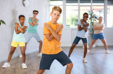Active preteen boy practicing sport dances with other children in training hall during dancing classes