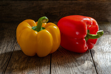 Yellow and red bell peppers on a wooden table.