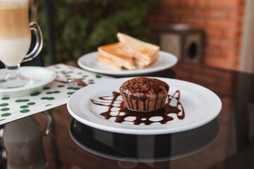 Chocolate cake with frosting in a small dish on a dark glass table.