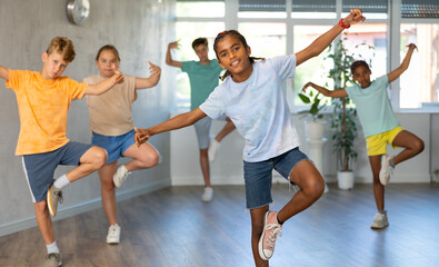 Fototapeta na wymiar Positive cheerful smiling children studying modern style dance in class indoors