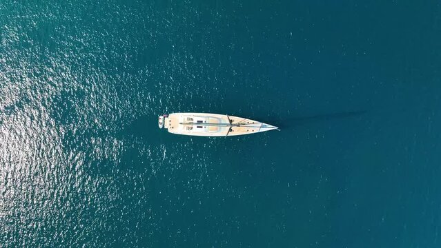 An aerial view of the sail yacht on the blue sea. Transparent clear water in the sea. Summer vacations and travels on a sailing yacht. Summer relaxation.