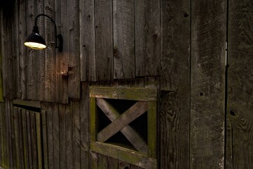 Rustic Charm Illuminated: Outdoor Wall Lamp Casting Light on an Old Wooden Barn, Captured in 4K Resolution