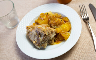 Stewed pork and cut potato pieces served in a plate with other table appointments