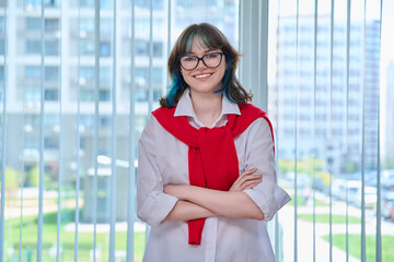 Smiling trendy female student looking at camera, posing in college classroom