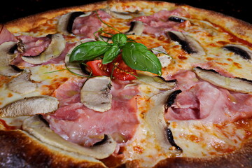 Pizza with ham, mushrooms and tomatoes on a black background - 619607415