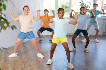 Confident dark-skinned tween girl krumper posing during workout in group dance class for children..
