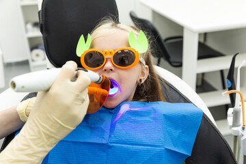 Little patient, adorable little child girl sitting in dentist's chair during appointment in pediatric dentistry clinic