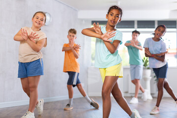 Fototapeta premium Smiling cute african american tween girl visiting group choreography class, learning modern dynamic dances. Concept of active lifestyle of children
