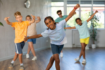 African boy performs movements during warm-up, limbering-up part of workout together with peers....