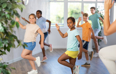 Fototapeta premium Dynamic little boys and girls attendees of dancing courses training Hip-hop dance poses in dancehall