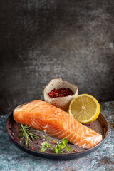 Fresh raw salmon fillet with ingredients for preparation.