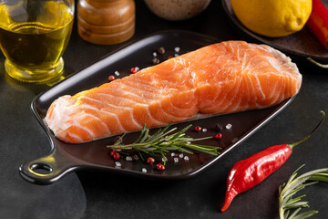 Fresh raw salmon fillet with ingredients for preparation.