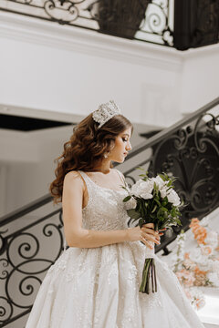 a girl in the image of a bride in a wedding dress with curly long brown hair holding a bouquet of flowers