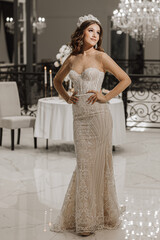 Fototapeta premium glamorous studio photo of a girl in a wedding dress. A large hanging chandelier. Luxurious interior in white style. Vertical photo
