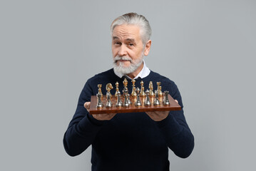 Man with chessboard and game pieces on light gray background