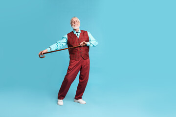 Cheerful senior man with walking cane on light blue background