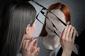 Suffering from hallucinations. Woman seeing her faceless reflection in broken mirror