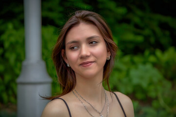 young woman look aside student with necklaces in a park on green background