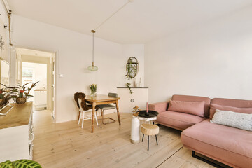 Fototapeta premium a living room with a pink couch and some plants on the table in front of the couch is an open door