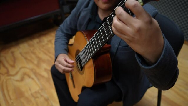 hispanic latin guitarist performing classical music, top view closeup on left hand of a classic nylon spanish guitar player, high angle shot