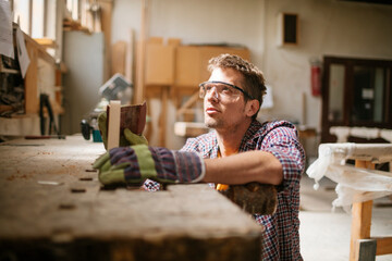 Young carpenter working in his woodworking workshop - obrazy, fototapety, plakaty