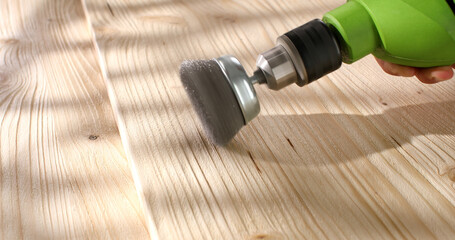 Wood brushing with wire cup brush for drill. Processing, aging and texturing of wood surface. Close up. Angle view.