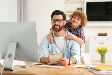 Man working remotely at home. Father with his child at desk