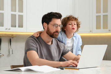 Man with laptop working remotely at home. Father and son at desk