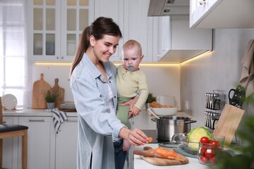 Happy young woman and her cute little baby cooking together in kitchen