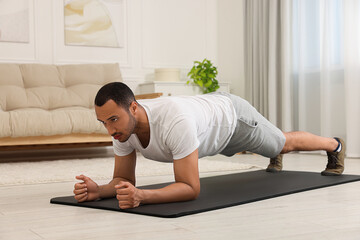 Man doing morning exercise on fitness mat at home