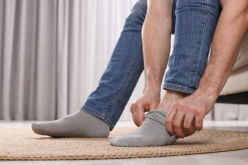 Fototapeta premium Man putting on grey socks at home, closeup