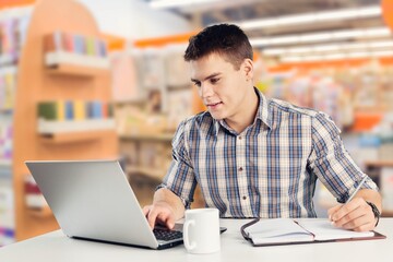 Positive busy student guy work with laptop