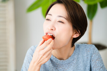 トマトを食べる若い女性　飲食イメージ	
