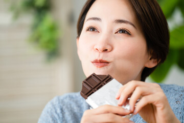 チョコレートを食べる若い女性　飲食イメージ	