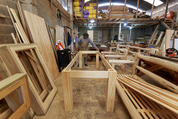 Crafting Perfection: Woodworker Measuring a Table's Side in a Carpentry Workshop