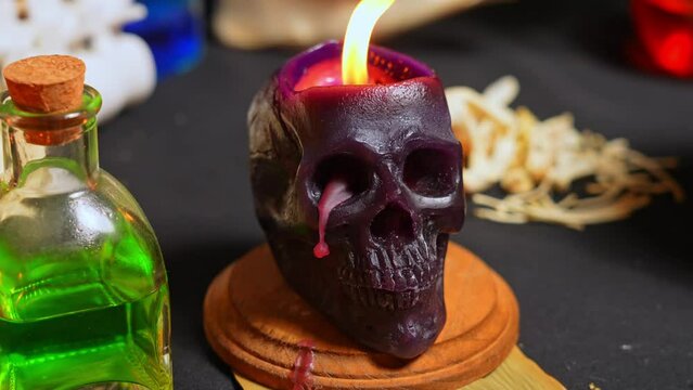 Black magic candles human skull with dark background, selective focus. Magical Halloween horror concept. Bee wax candles burning very quick. Macabre and darkness mood set up.