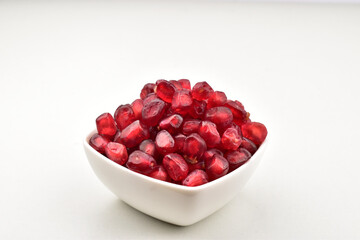 Pomegranate seeds in bowl on white background