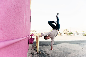 Photos of an acrobatic young man near an urban mural. 