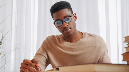 Studying focus. Exam research. Homework preparation. Tired young man in glasses reading book...