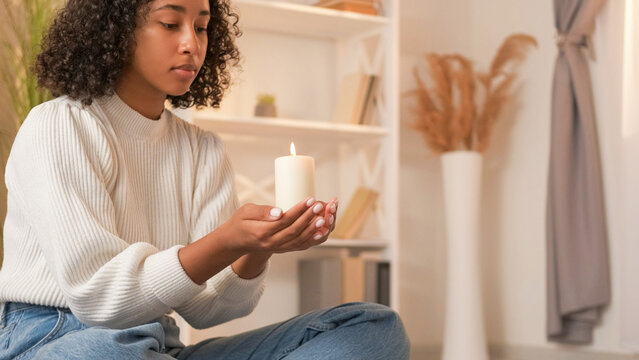 Candle meditation. All Soul's Day. Holocaust remembrance. Serious faithful woman praying in memory of dead with burning flame wax light at home copy space.