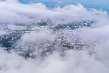 Fog covers the city and houses. A beautiful aerial view of Chiang Mai Thailand with sea fog covering the building, airport and parts of the city. Revealing part of the business building and road