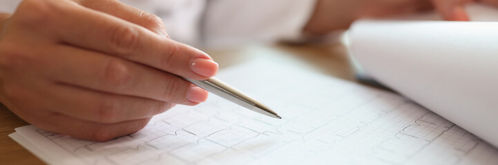 Professional woman doctor looking at cardiogram to analyze results