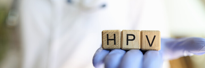 Female practitioner hand holding wooden cubes with word hpv