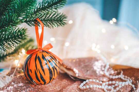 Christmas balls painted as tiger stripes on Christmas tree with a garland. 2022 is a year of the Tiger. Happy New Year . Symbol of year lunar chinese calendar tiger on Christmas ball .
