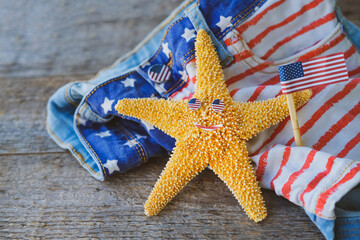 Starfish holding an American flag against a background of clothing with a usa print. Labor day holiday concept. 4th of July USA Independence Day. Copy space for text.