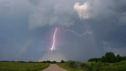 Lightning strike over the rainbow. Stormy landscape.