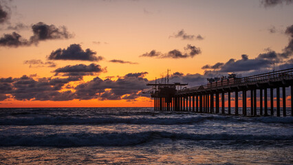 Sunset through the pier at the La Jolla beach