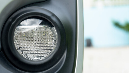 Front view of round fog lamp of car. and blurred outdoor blue wall.